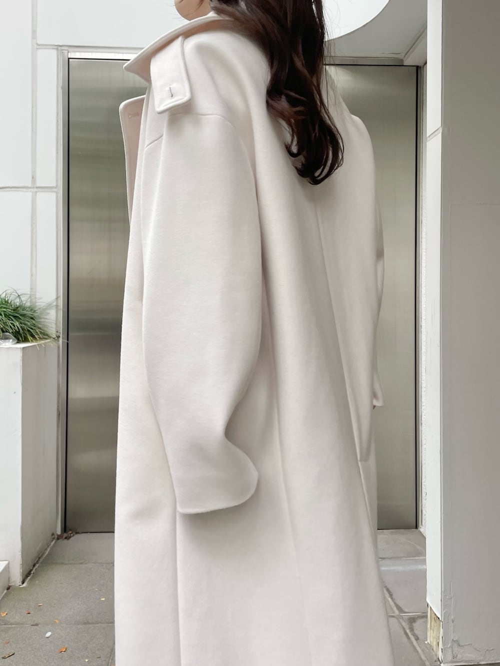 ホワイト系のステンカラーコート、ベージュ系のワンピース、ベージュ系のブーツを着用したレディースの秋コーディネートの5枚目の写真