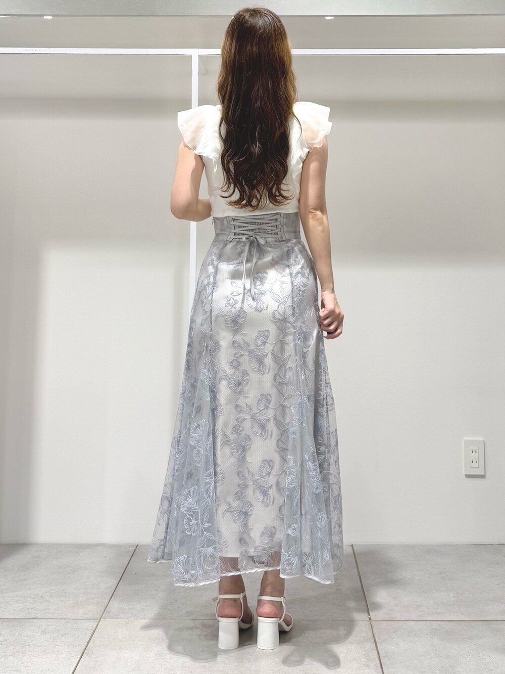 ホワイト系のニット/セーター、ブルー系のスカート、ホワイト系のサンダルを着用したレディースの春コーディネートの3枚目の写真