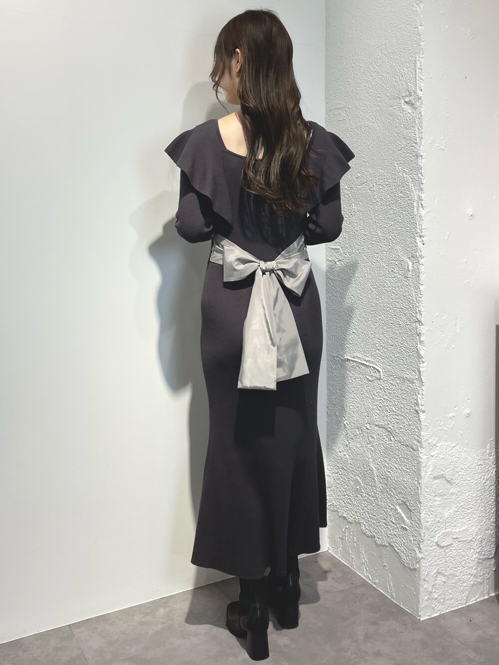 グレー系のワンピース、ブラック系のブーツを着用したレディースの冬コーディネートの2枚目の写真