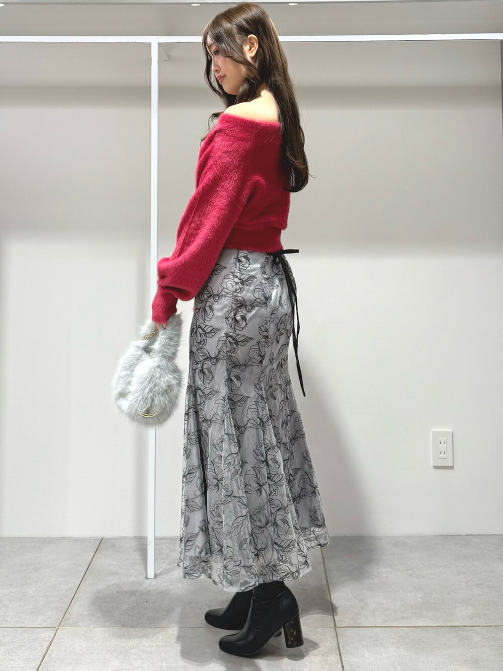 レッド系のニット/セーター、グレー系のハンドバッグ、グレー系のスカートを着用したレディースの秋コーディネートの3枚目の写真