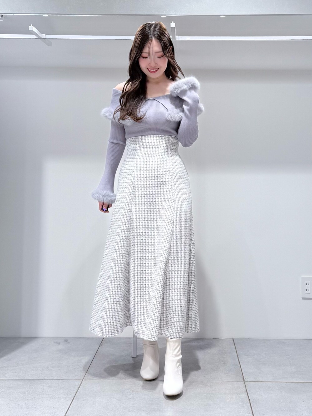 ホワイト系のチェスターコート、ホワイト系のスカート、グレー系のニット/セーターを着用したレディースの冬コーディネートの7枚目の写真