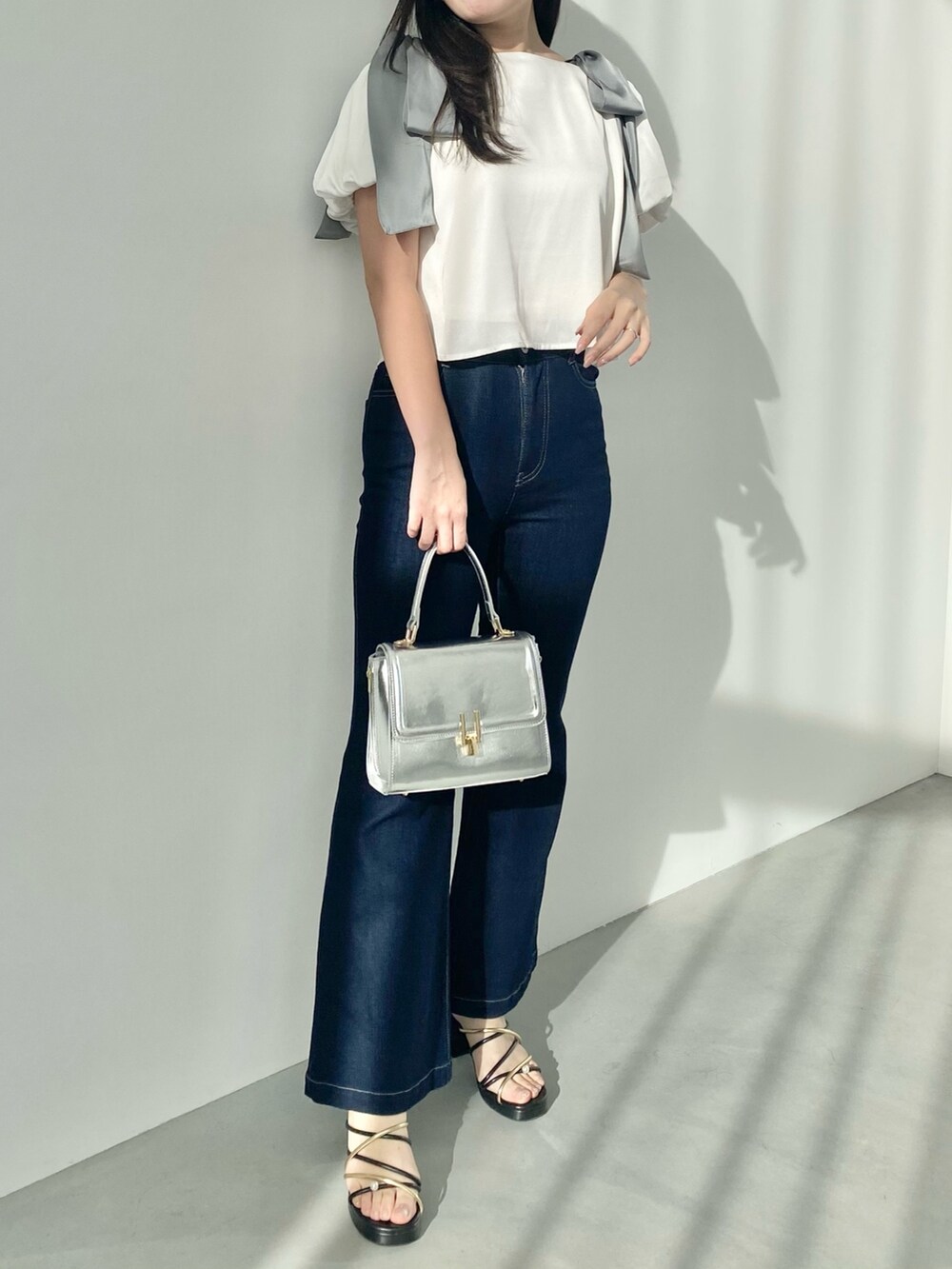 ホワイト系のシャツ/ブラウス、ブルー系のデニムパンツ、ブラック系のサンダルを着用したレディースの春コーディネートの2枚目の写真