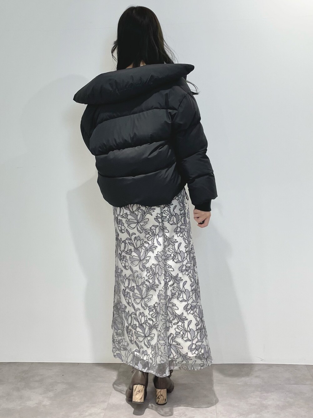 グレー系のスカート、ブラウン系のブーツ、ブラック系のダウンジャケット/コートを着用したレディースの冬コーディネートの4枚目の写真