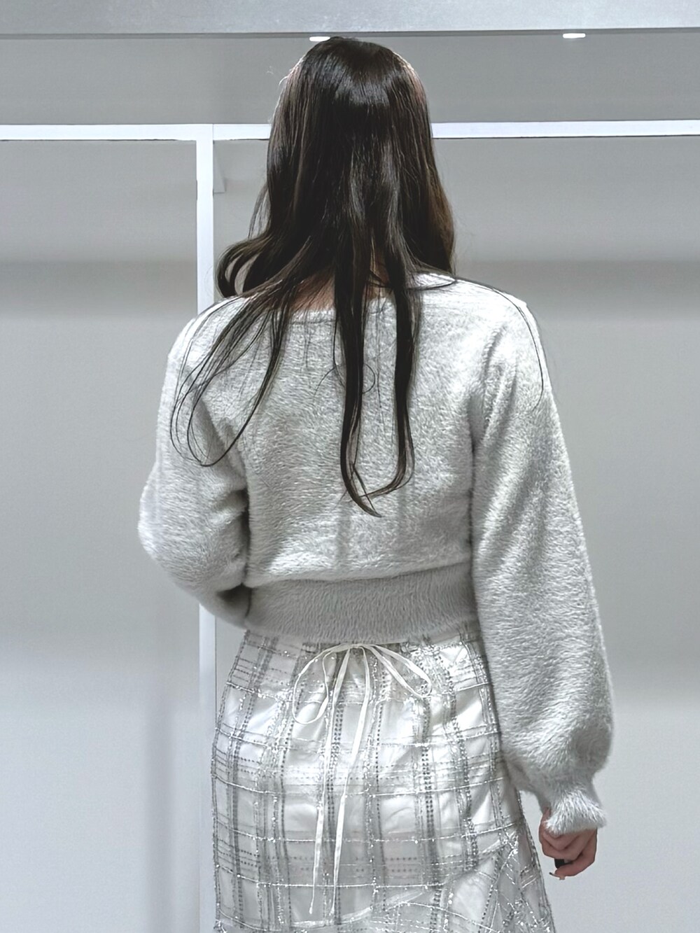 グレー系のカーディガン/ボレロ、ホワイト系のスカート、ホワイト系のブーツを着用したレディースの秋コーディネートの6枚目の写真