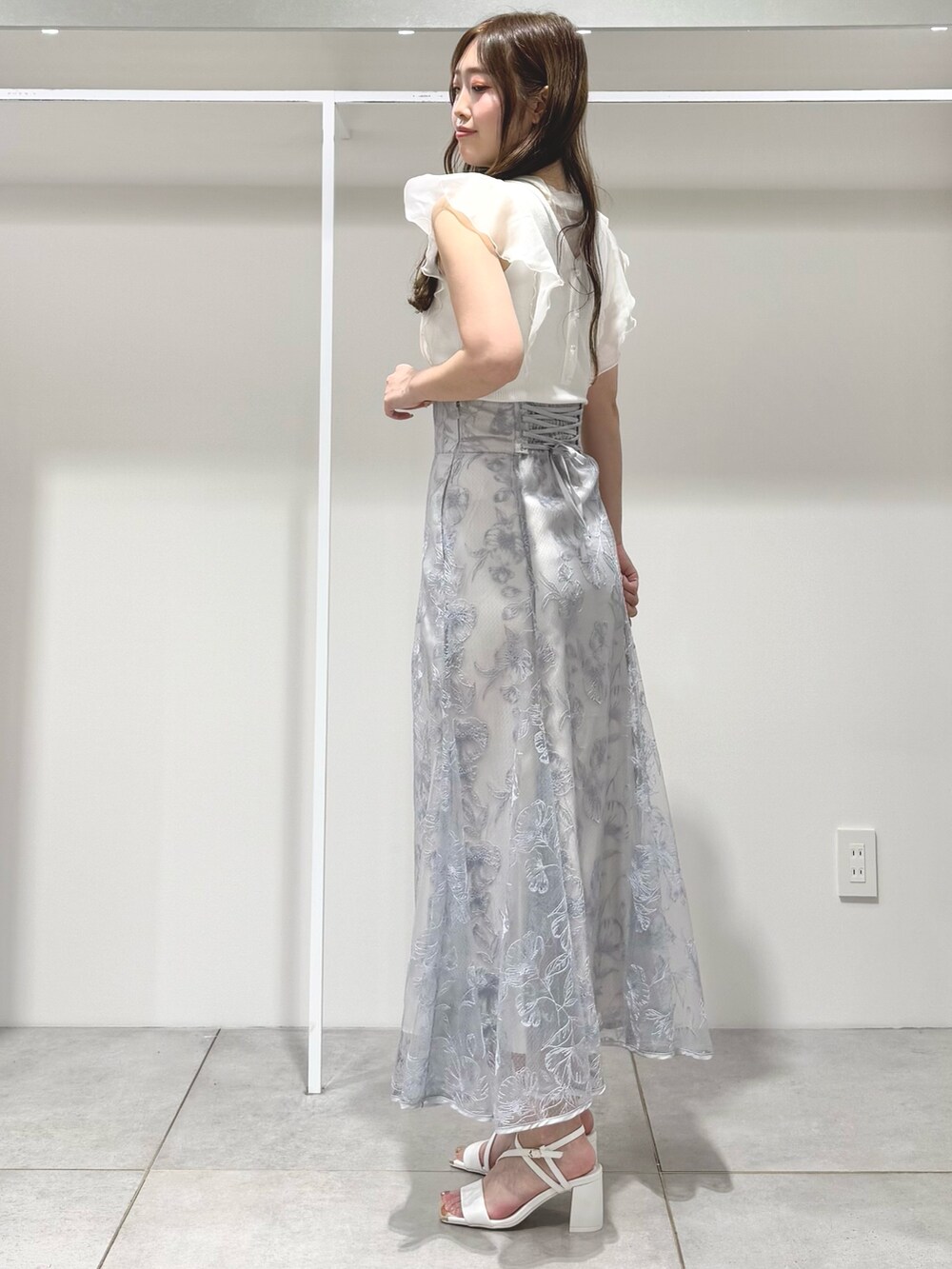 ホワイト系のニット/セーター、ブルー系のスカート、ホワイト系のサンダルを着用したレディースの春コーディネートの2枚目の写真