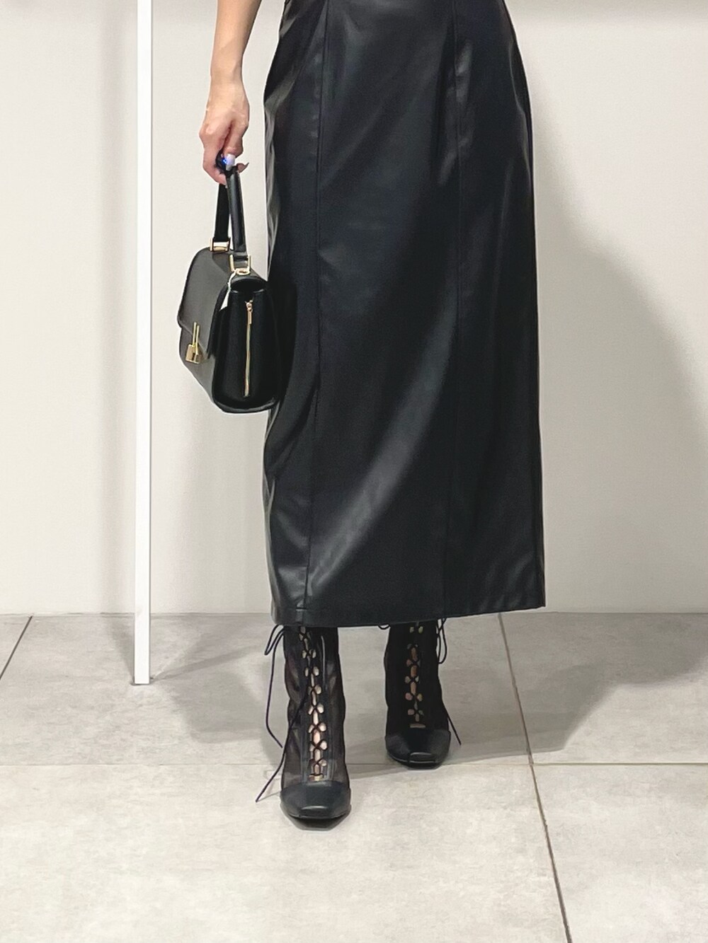 グレー系のニット/セーター、ブラック系のスカート、ブラック系のショルダーバッグを着用したレディースの秋コーディネートの7枚目の写真