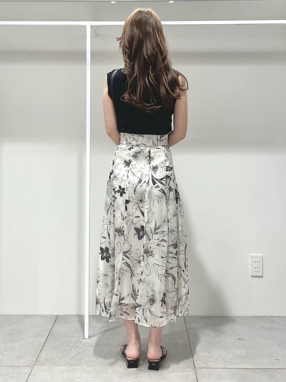 ブラック系のニット/セーター、ホワイト系のスカート、ブラック系のサンダルを着用したレディースの春コーディネートの3枚目の写真