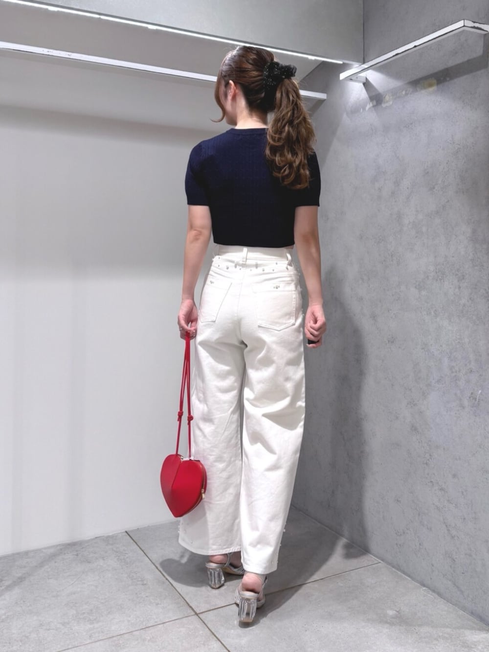シルバー系のサンダル、ホワイト系のデニムパンツ、レッド系のショルダーバッグを着用したレディースの夏コーディネートの3枚目の写真