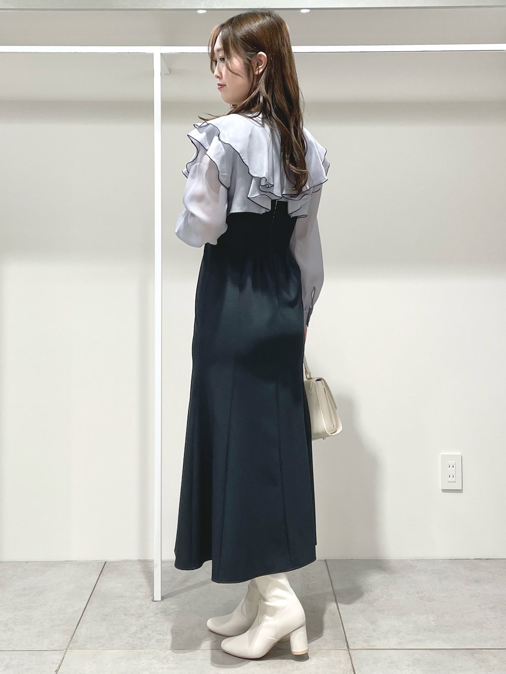 グレー系のワンピース、ホワイト系のブーツ、ホワイト系のハンドバッグを着用したレディースの冬コーディネートの3枚目の写真