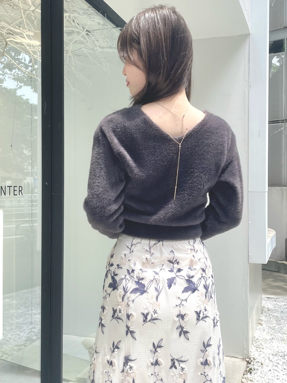 ブラック系のハンドバッグ、ブラウン系のブーツ、グレー系のスカートを着用したレディースの秋コーディネートの6枚目の写真