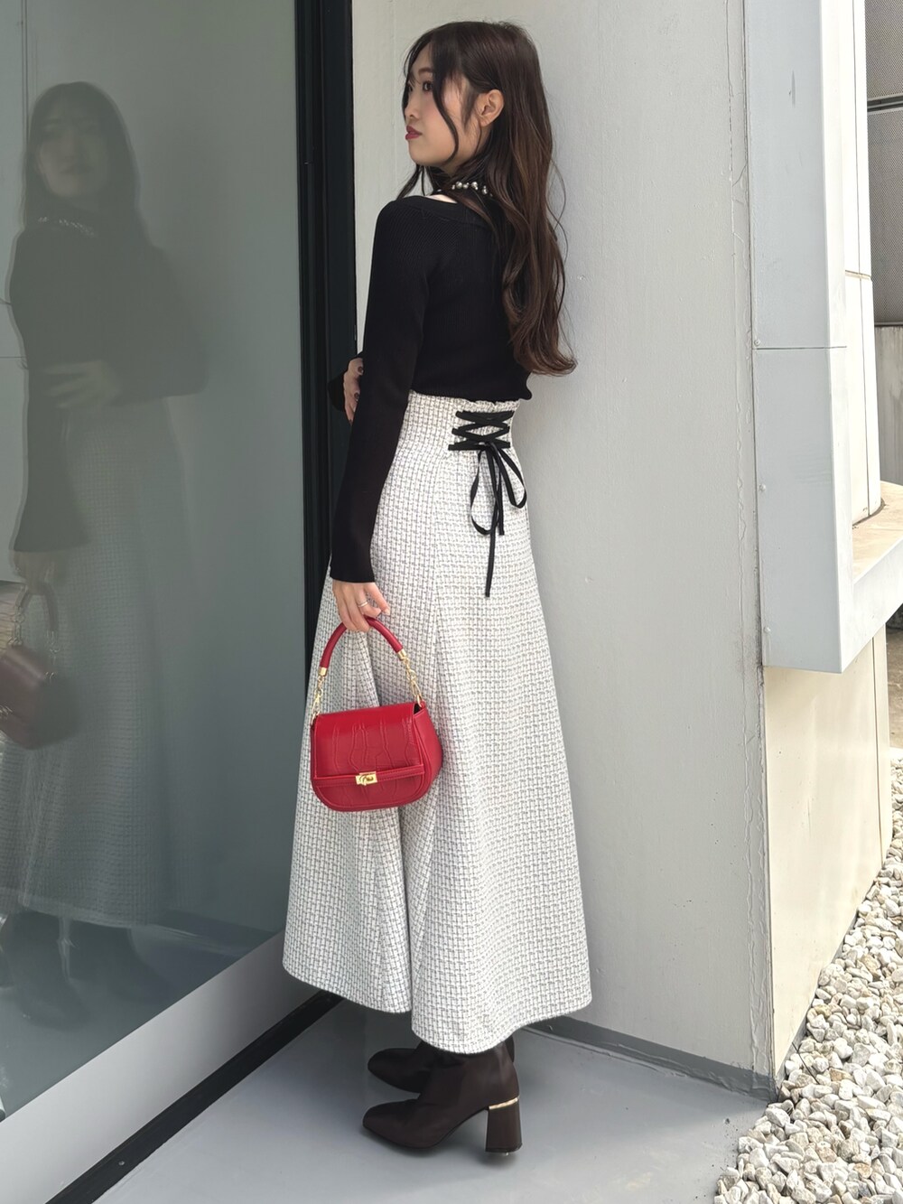 ブラック系のニット/セーター、レッド系のハンドバッグ、ホワイト系のスカートを着用したレディースの冬コーディネートの3枚目の写真