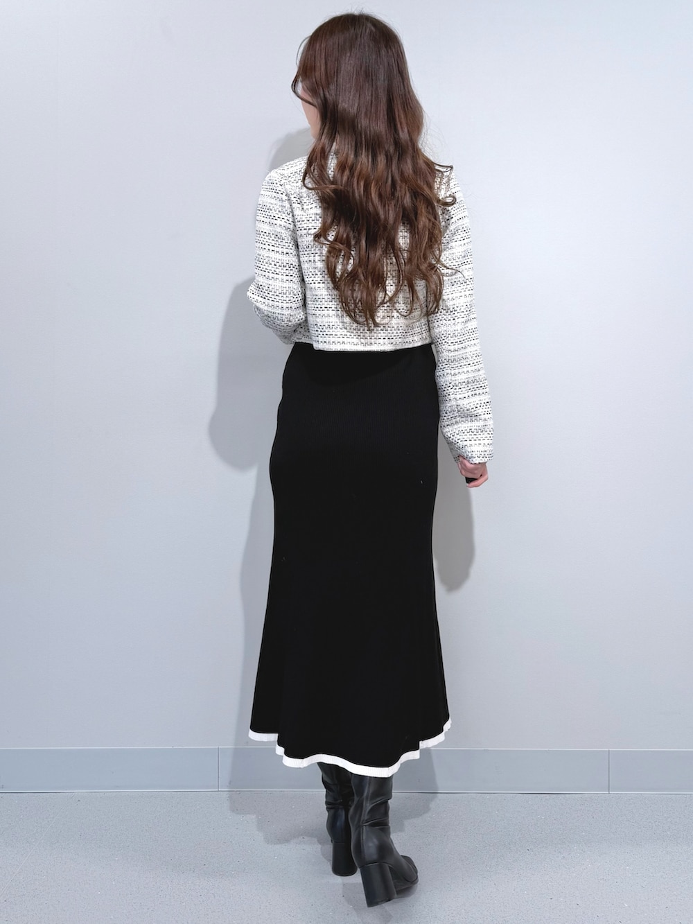 ホワイト系のテーラードジャケット、ブラック系のワンピース、ブラック系のブーツを着用したレディースの冬コーディネートの3枚目の写真