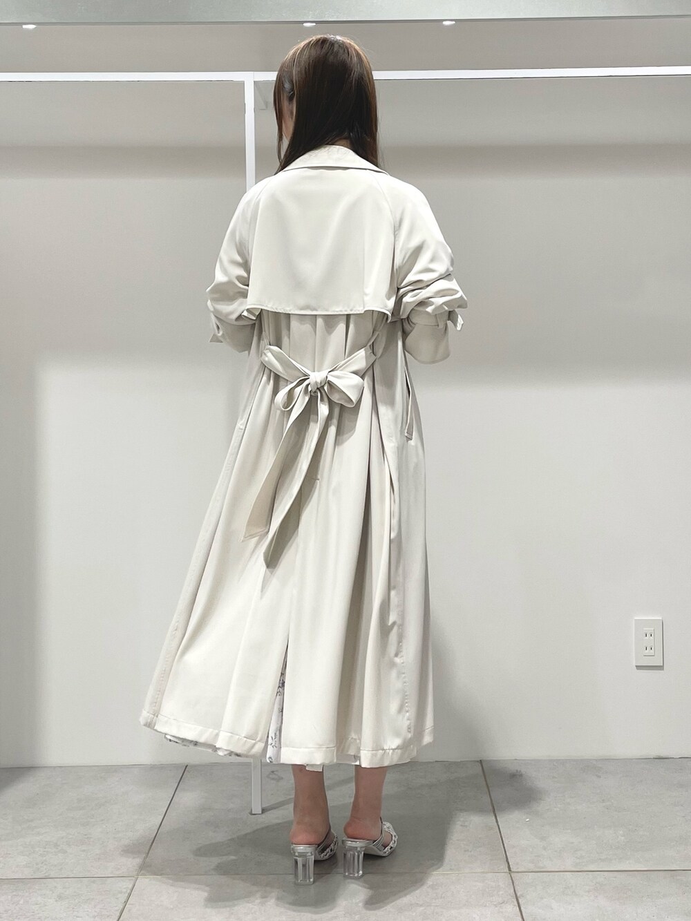 ホワイト系のトレンチコート、ホワイト系のワンピース、シルバー系のパンプスを着用したレディースの春コーディネートの3枚目の写真
