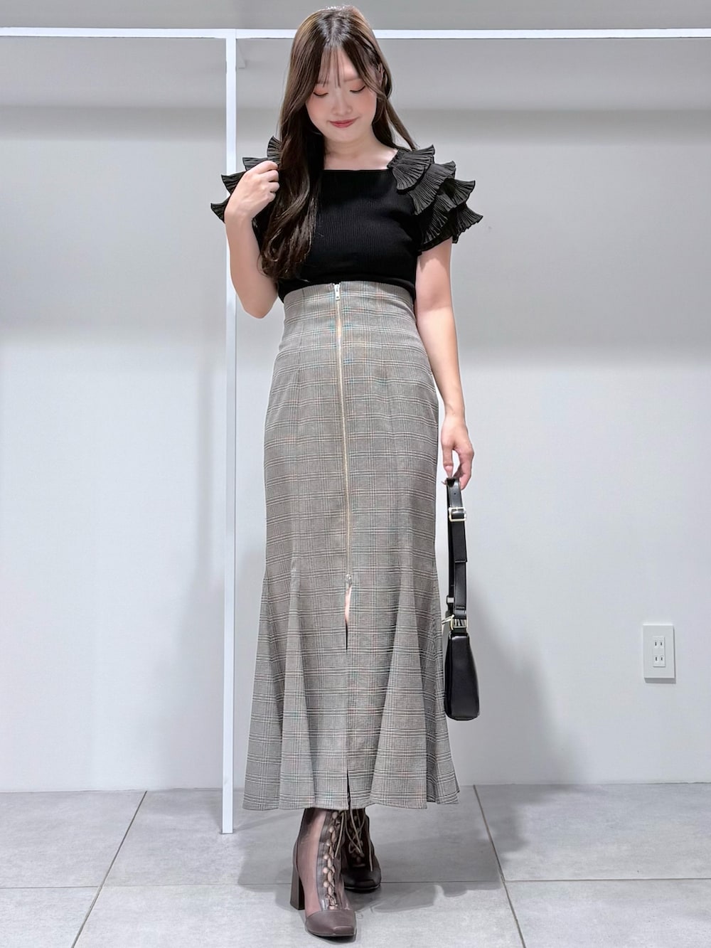 その他のスカート、ブラック系のニット/セーター、ブラック系のハンドバッグを着用したレディースの夏コーディネートの2枚目の写真