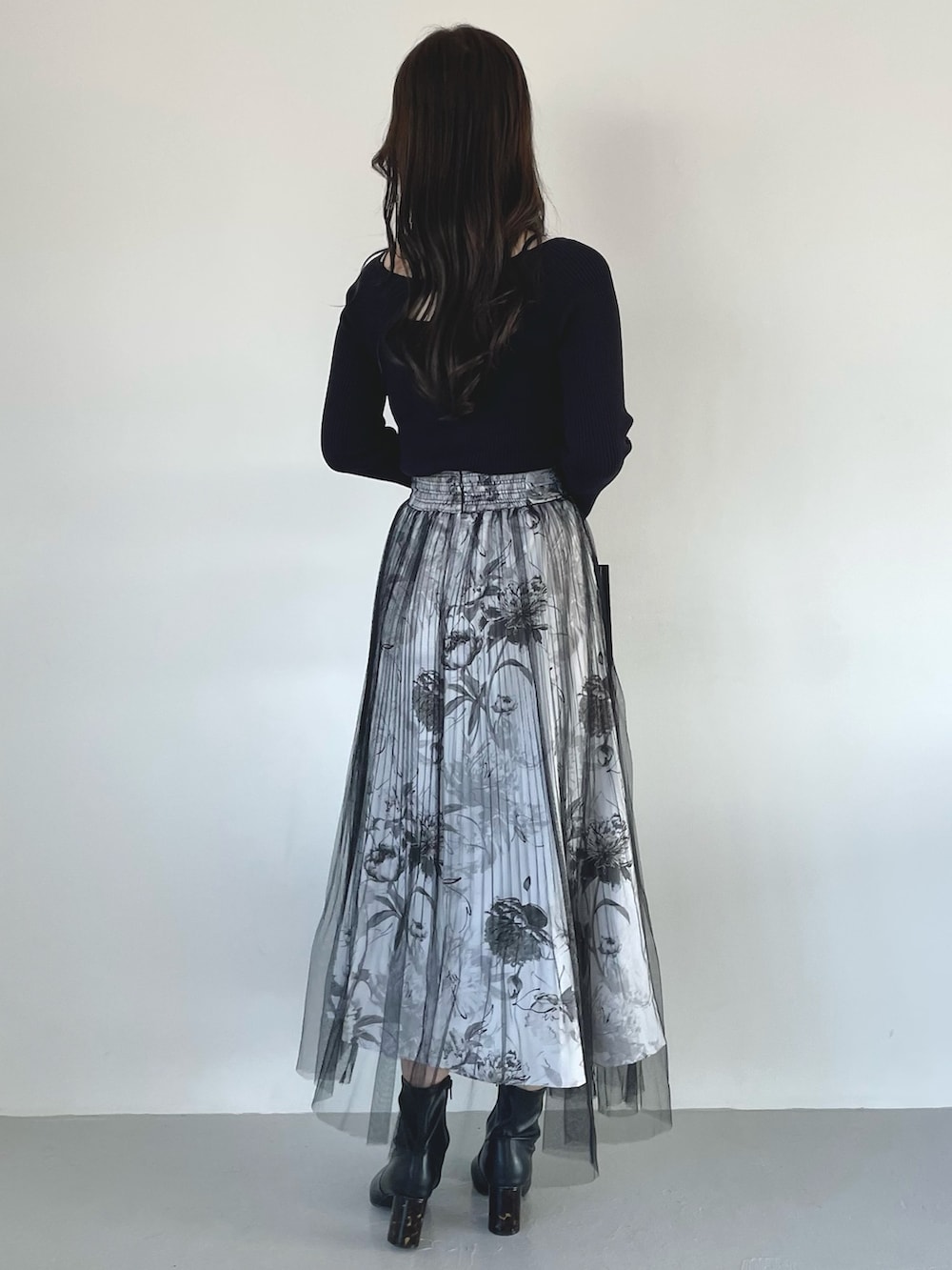 ブラック系のブーツ、ブラック系のスカート、ブラック系のハンドバッグを着用したレディースの春コーディネートの5枚目の写真