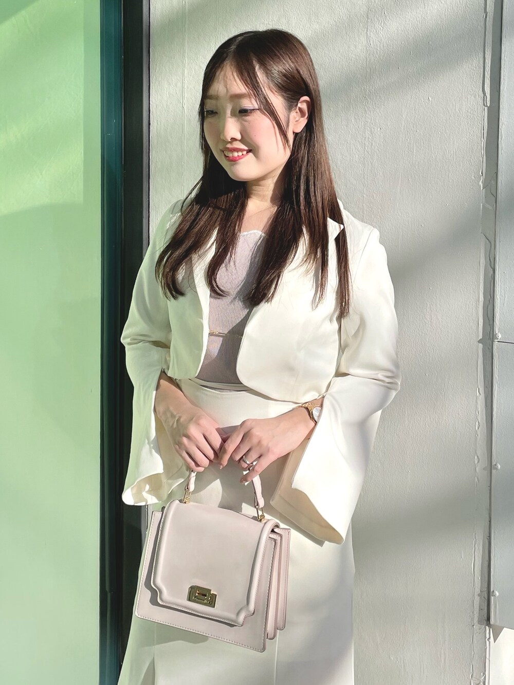 ピンク系のニット/セーター、ホワイト系のテーラードジャケット、ホワイト系のスカートを着用したレディースの春コーディネートの4枚目の写真