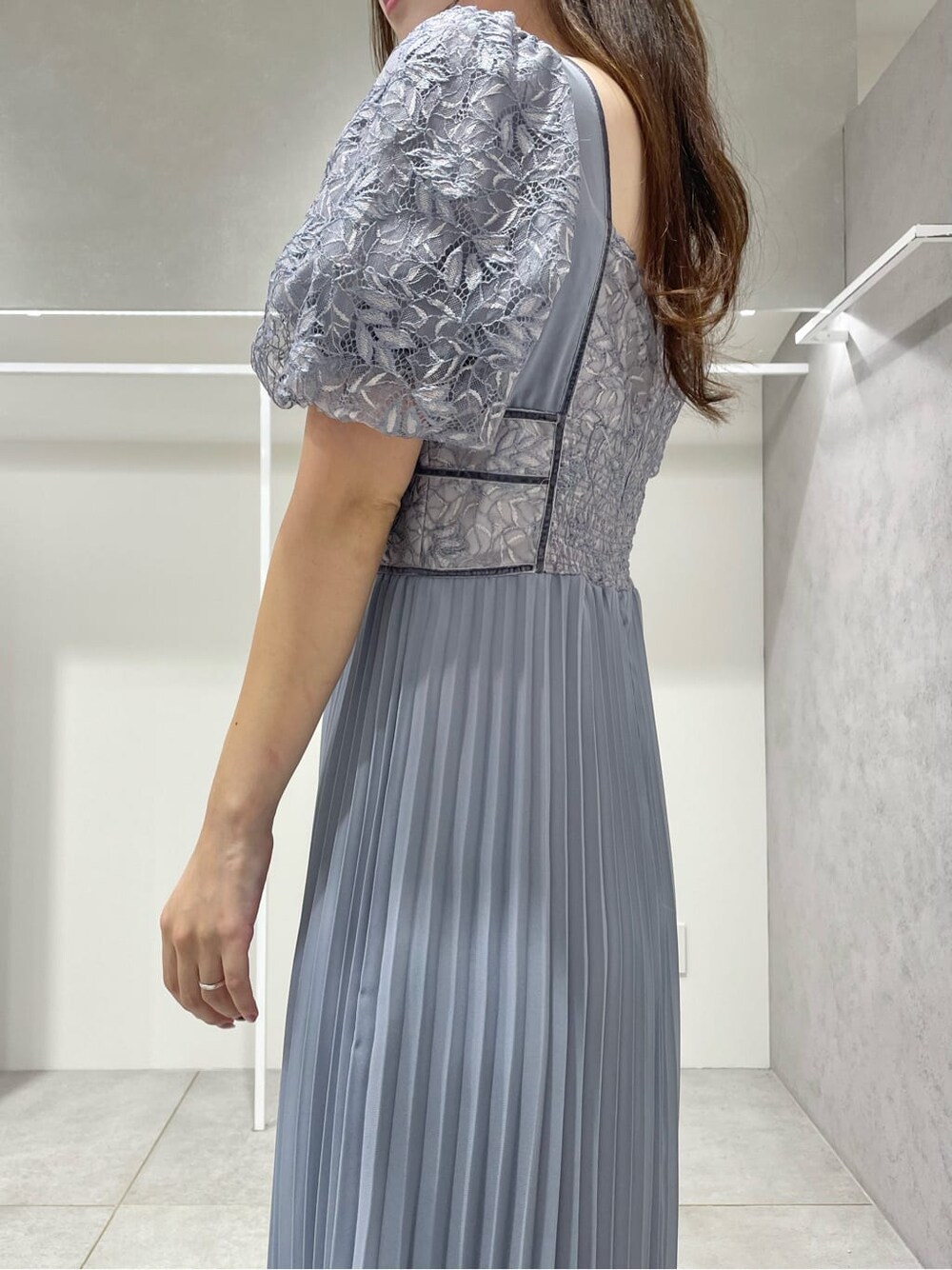 ブラック系のパンプス、ブルー系のワンピース、シルバー系のイヤリングを着用したレディースの秋コーディネートの6枚目の写真