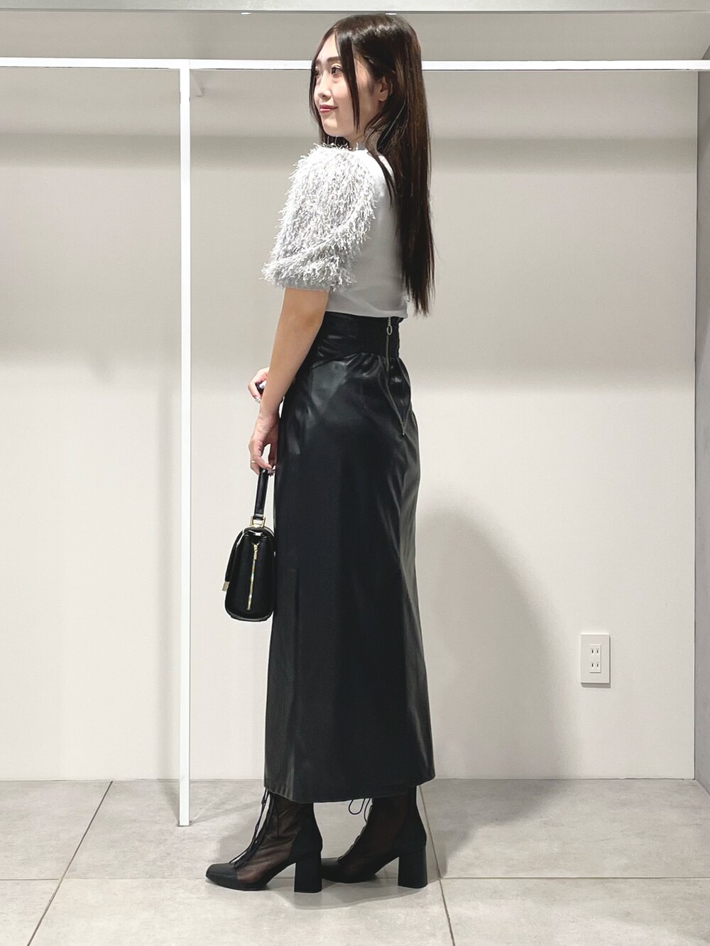 グレー系のニット/セーター、ブラック系のスカート、ブラック系のショルダーバッグを着用したレディースの秋コーディネートの3枚目の写真