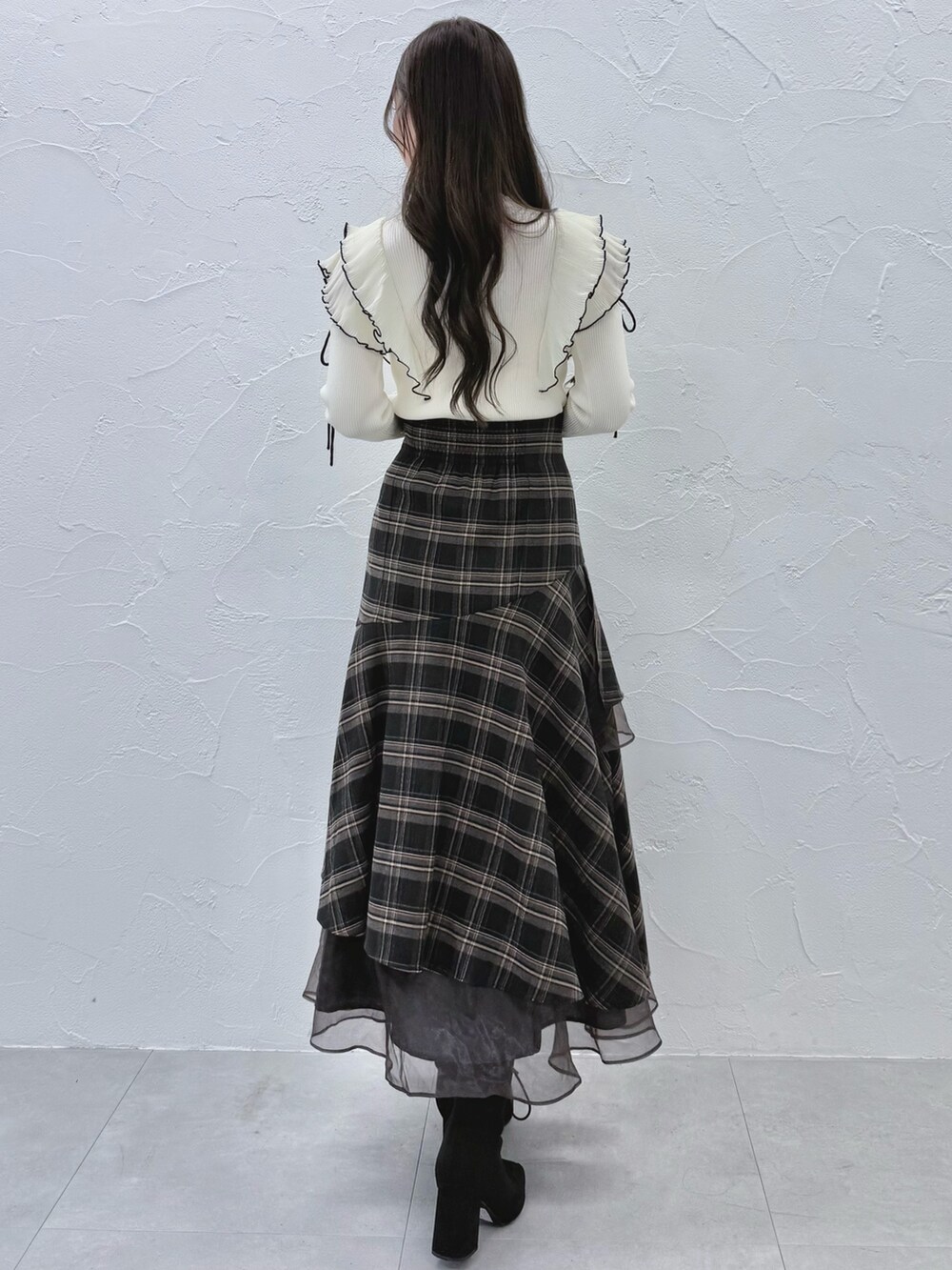 グレー系のスカート、ブラック系のブーツ、ホワイト系のニット/セーターを着用したレディースの秋コーディネートの3枚目の写真