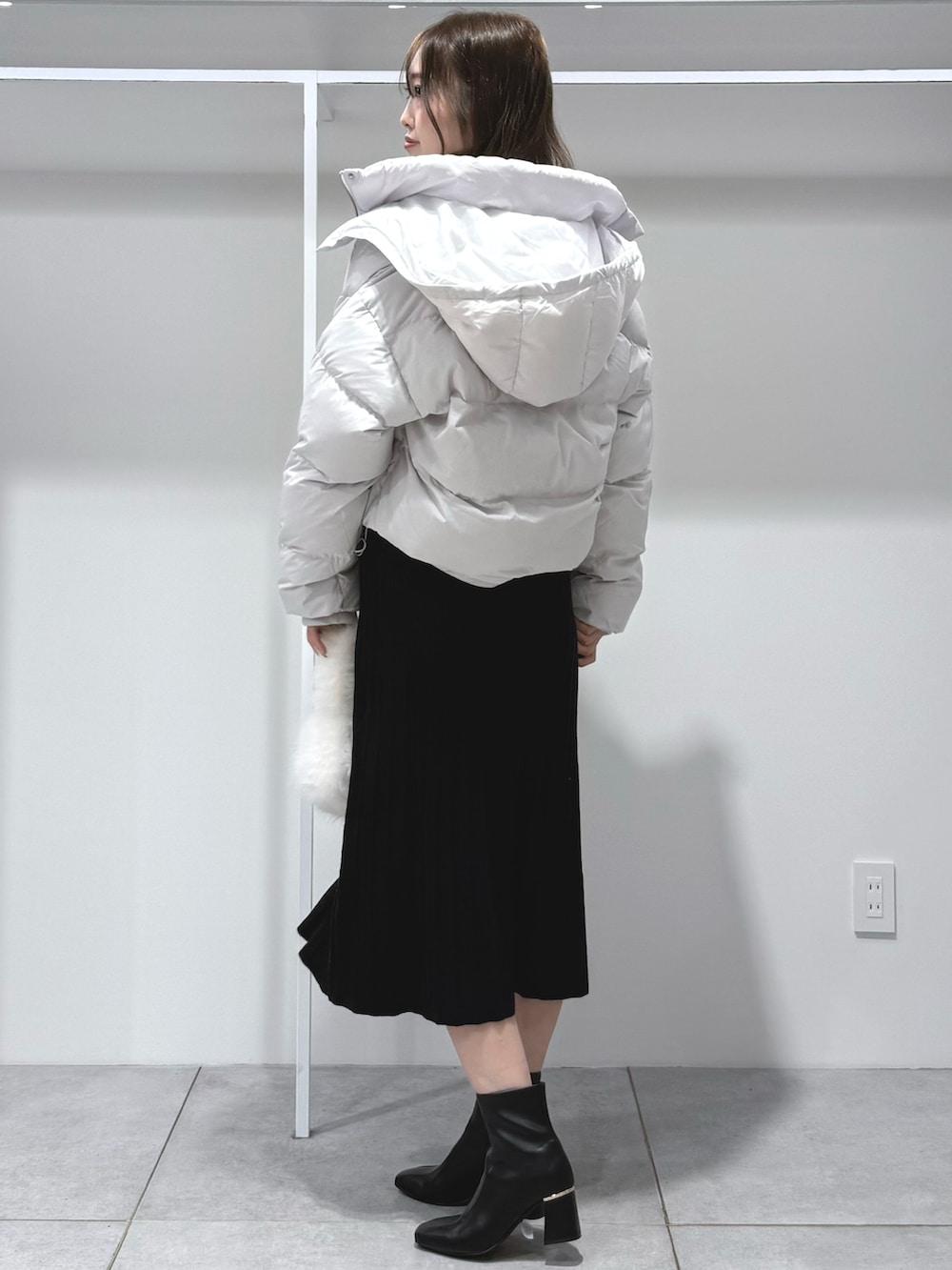 ブラック系のワンピース、ホワイト系のハンドバッグ、ブラック系のブーツを着用したレディースの秋コーディネートの3枚目の写真