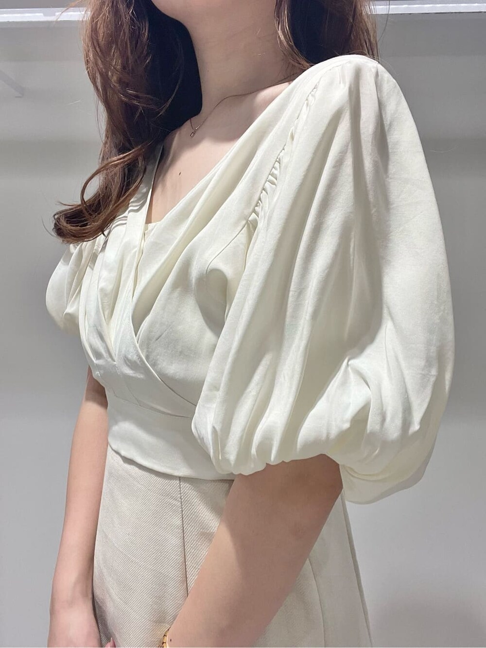 ベージュ系のサンダル、ベージュ系のトートバッグ、ホワイト系のワンピースを着用したレディースの春コーディネートの4枚目の写真