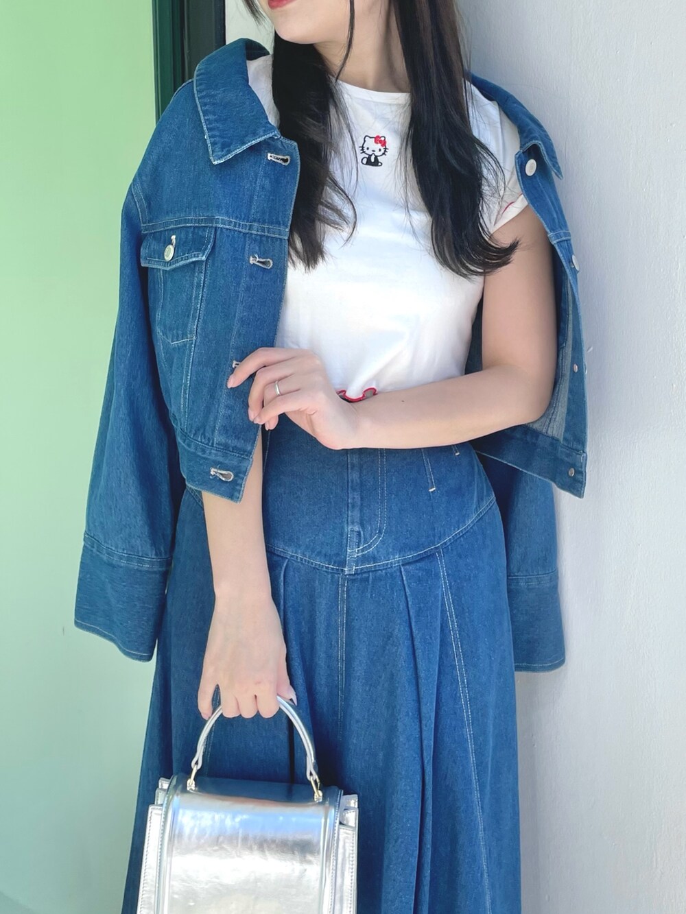 ブルー系のスカート、シルバー系のハンドバッグ、シルバー系のパンプスを着用したレディースの春コーディネートの4枚目の写真