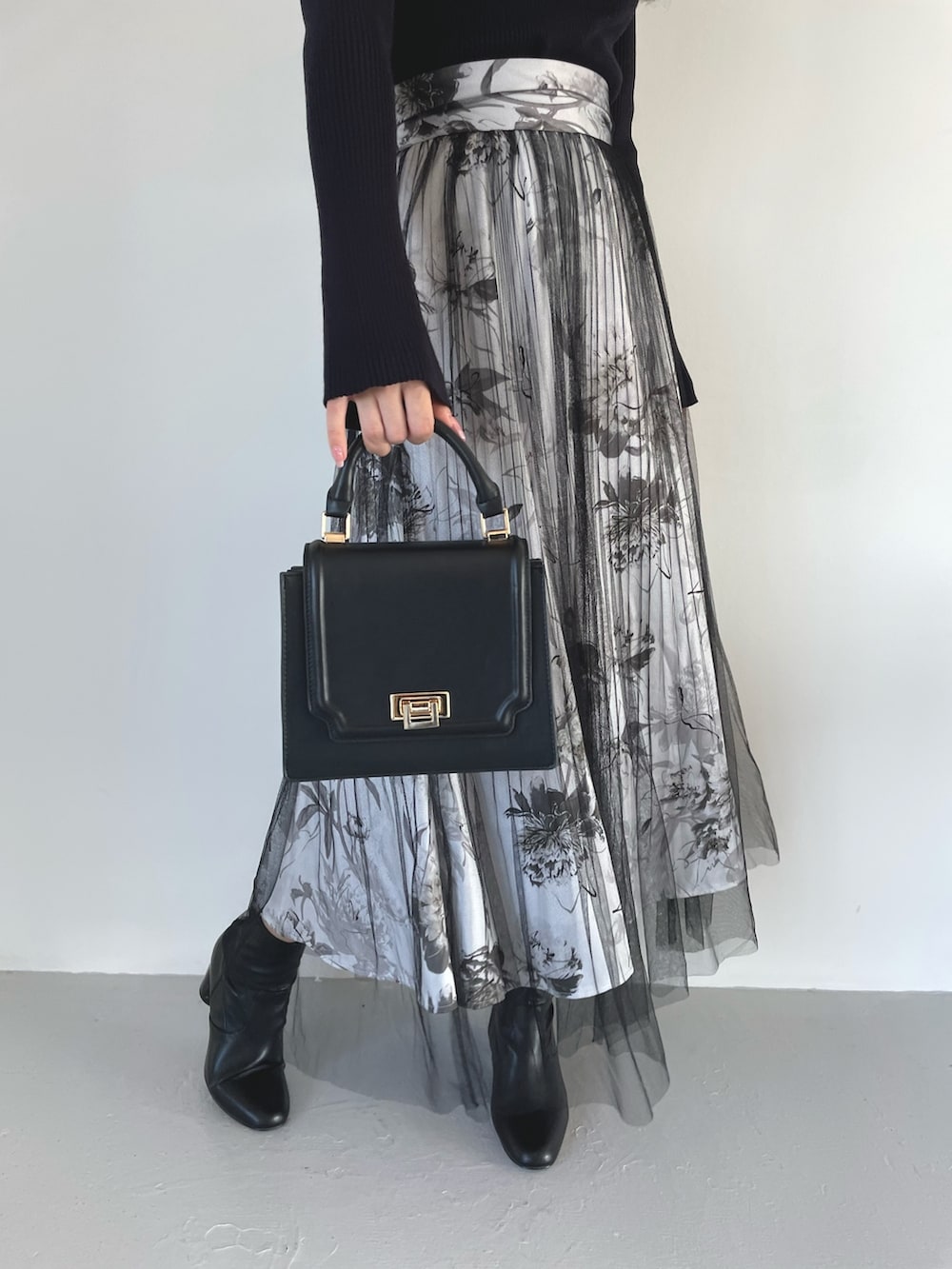 ブラック系のブーツ、ブラック系のスカート、ブラック系のハンドバッグを着用したレディースの春コーディネートの8枚目の写真
