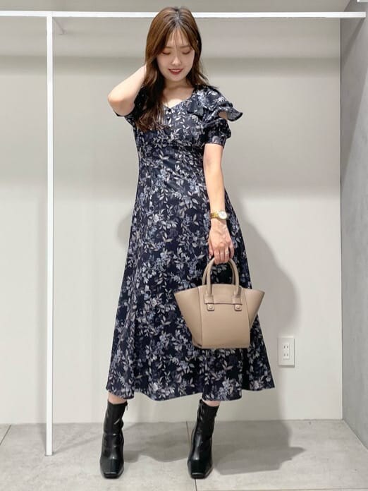 ブルー系のワンピース、ブラック系のブーツ、ブラウン系のハンドバッグを着用したレディースの秋コーディネートの2枚目の写真