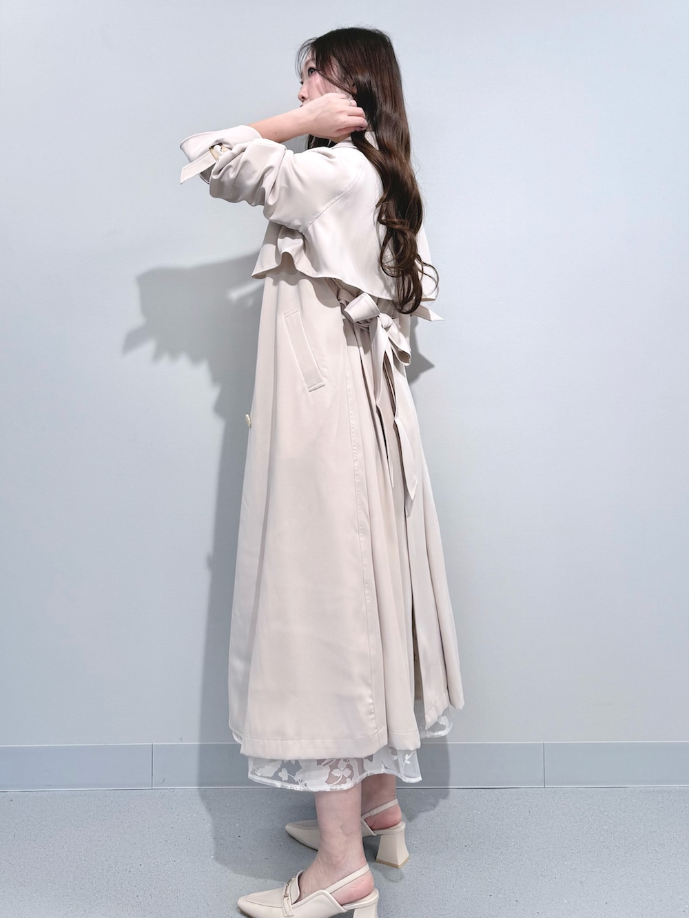 ベージュ系のワンピース、ホワイト系のパンプス、ホワイト系のトレンチコートを着用したレディースの冬コーディネートの3枚目の写真