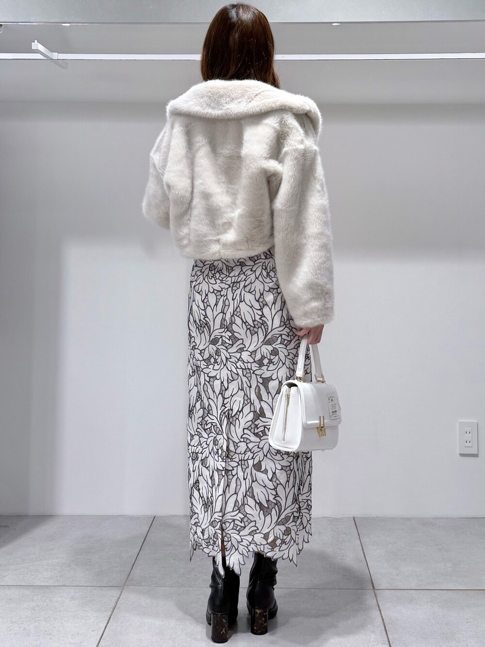 ホワイト系のその他アウター、ブラック系のブーツ、ホワイト系のハンドバッグを着用したレディースの冬コーディネートの4枚目の写真