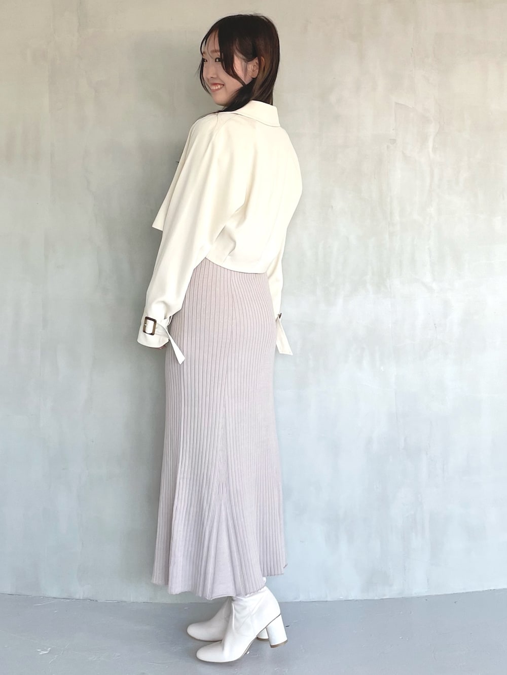 ベージュ系のトレンチコート、ピンク系のワンピース、ホワイト系のブーツを着用したレディースの冬コーディネートの2枚目の写真