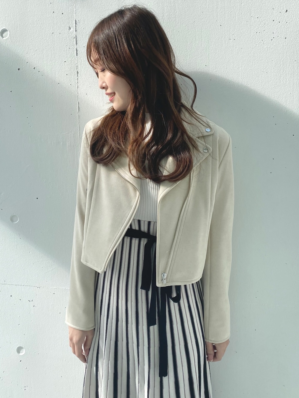 ホワイト系のワンピース、ベージュ系のライダースジャケットを着用したレディースの春コーディネートの4枚目の写真