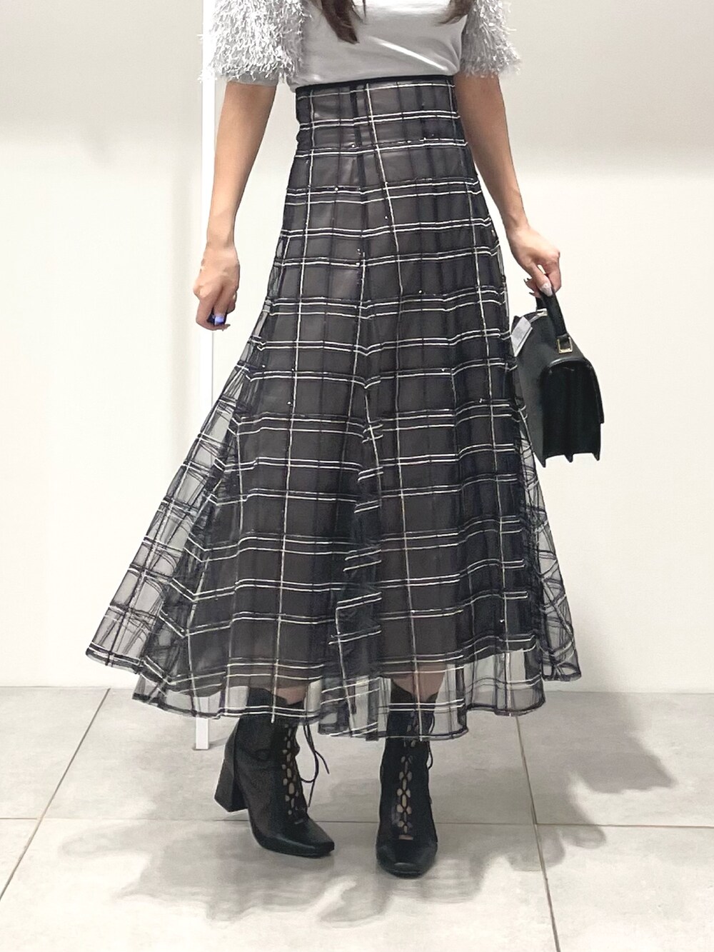 グレー系のニット/セーター、ブラック系のハンドバッグ、ブラック系のスカートを着用したレディースの秋コーディネートの7枚目の写真