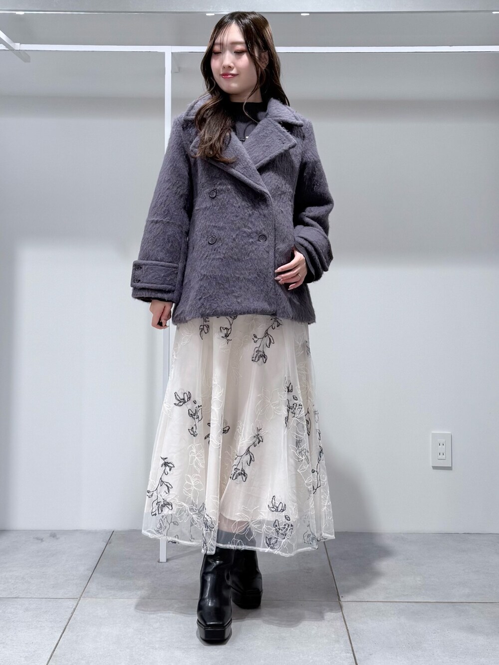 グレー系のその他アウター、グレー系のニット/セーター、ホワイト系のスカートを着用したレディースの冬コーディネートの2枚目の写真