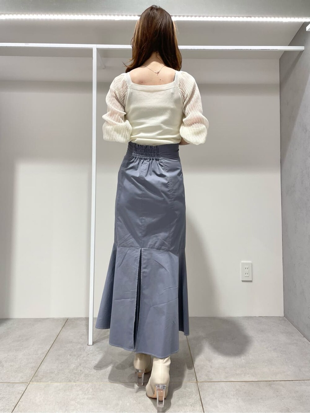 ブルー系のスカート、ホワイト系のニット/セーターを着用したレディースの春コーディネートの3枚目の写真