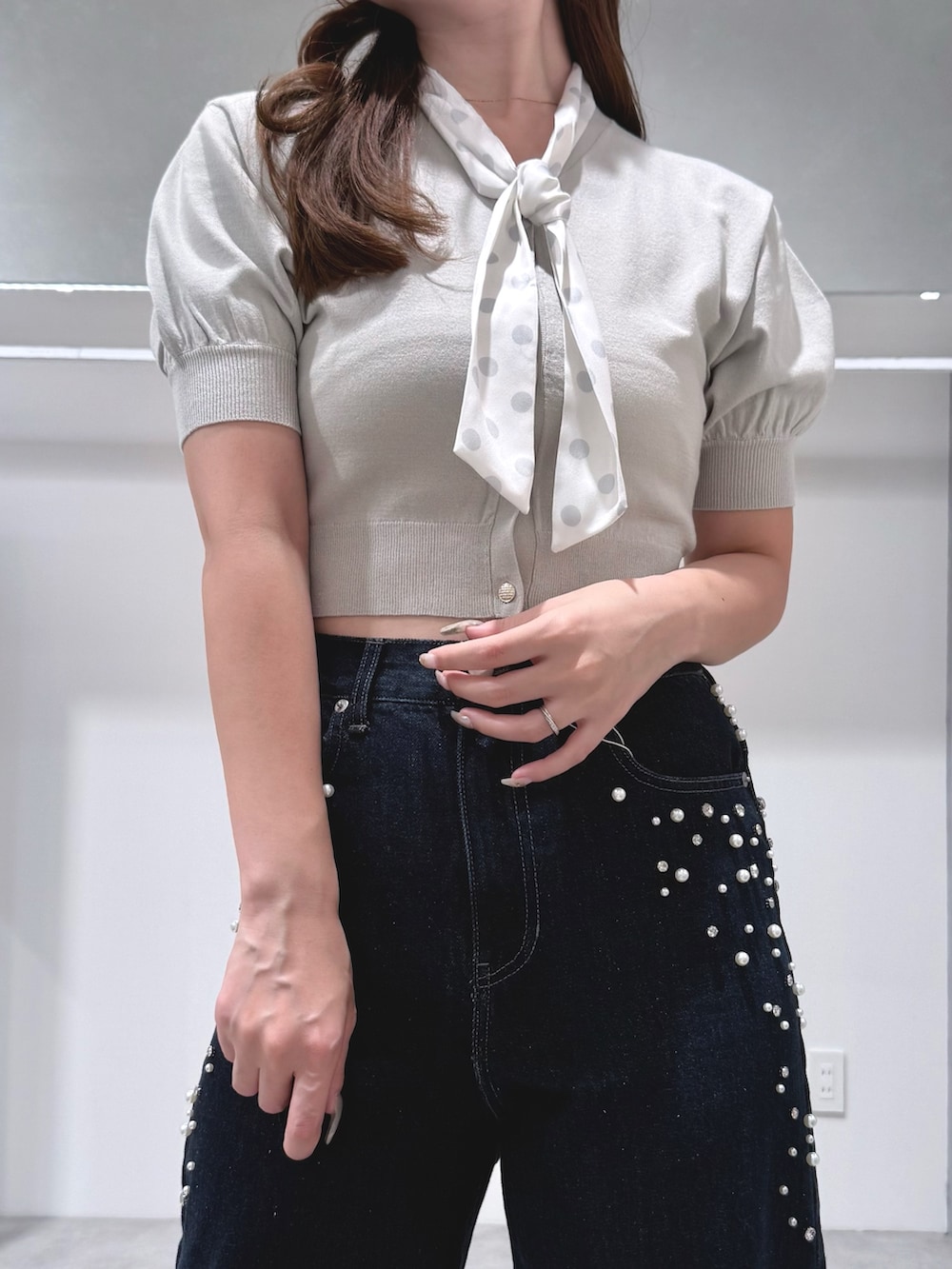 グリーン系のニット/セーター、ブルー系のデニムパンツ、ブラウン系のハンドバッグを着用したレディースの夏コーディネートの4枚目の写真