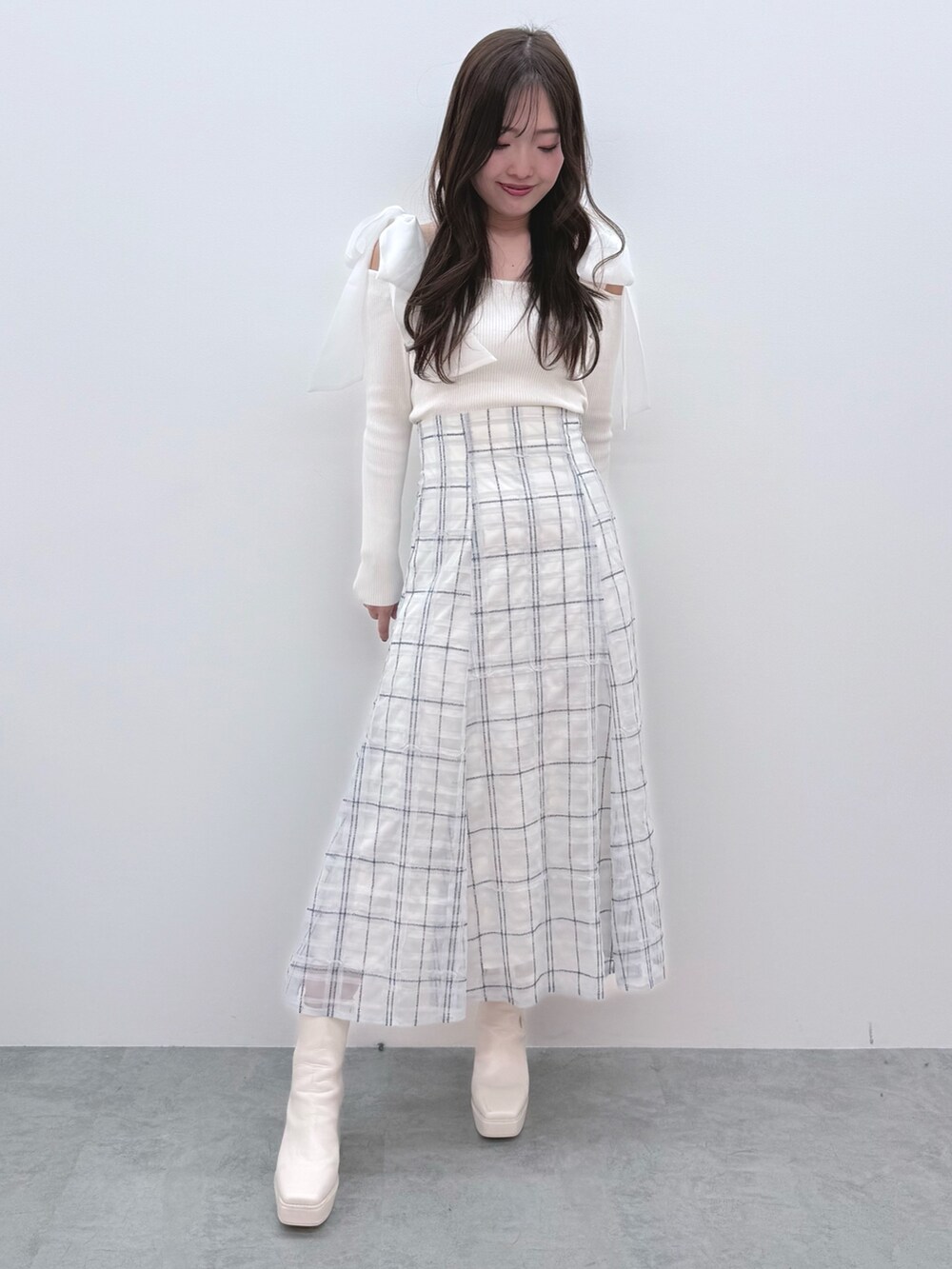ホワイト系のニット/セーター、ブルー系のスカート、ホワイト系のブーツを着用したレディースの冬コーディネートの2枚目の写真