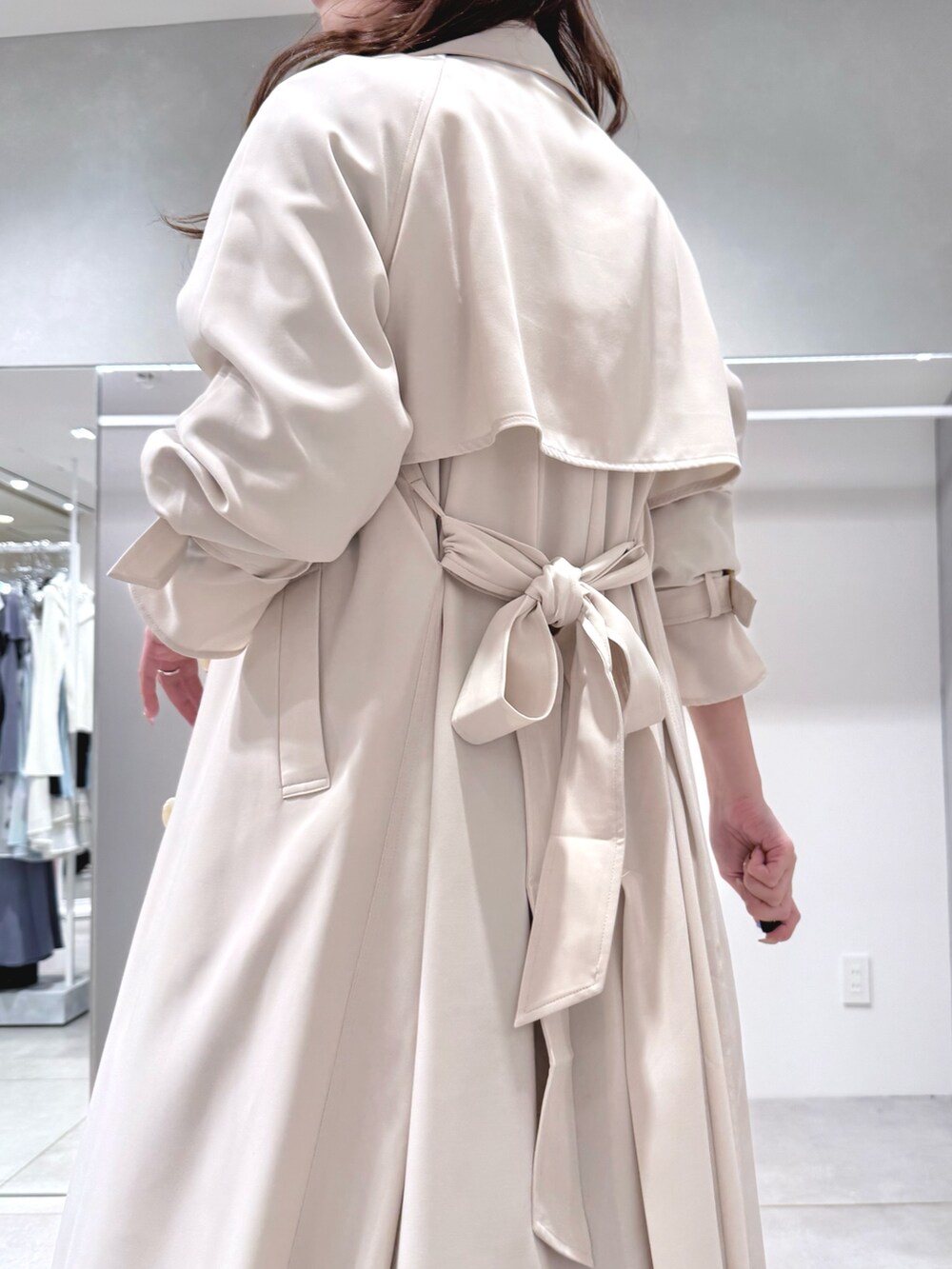 ホワイト系のトレンチコート、ブラック系のワンピース、ブラック系のブーツを着用したレディースの冬コーディネートの6枚目の写真