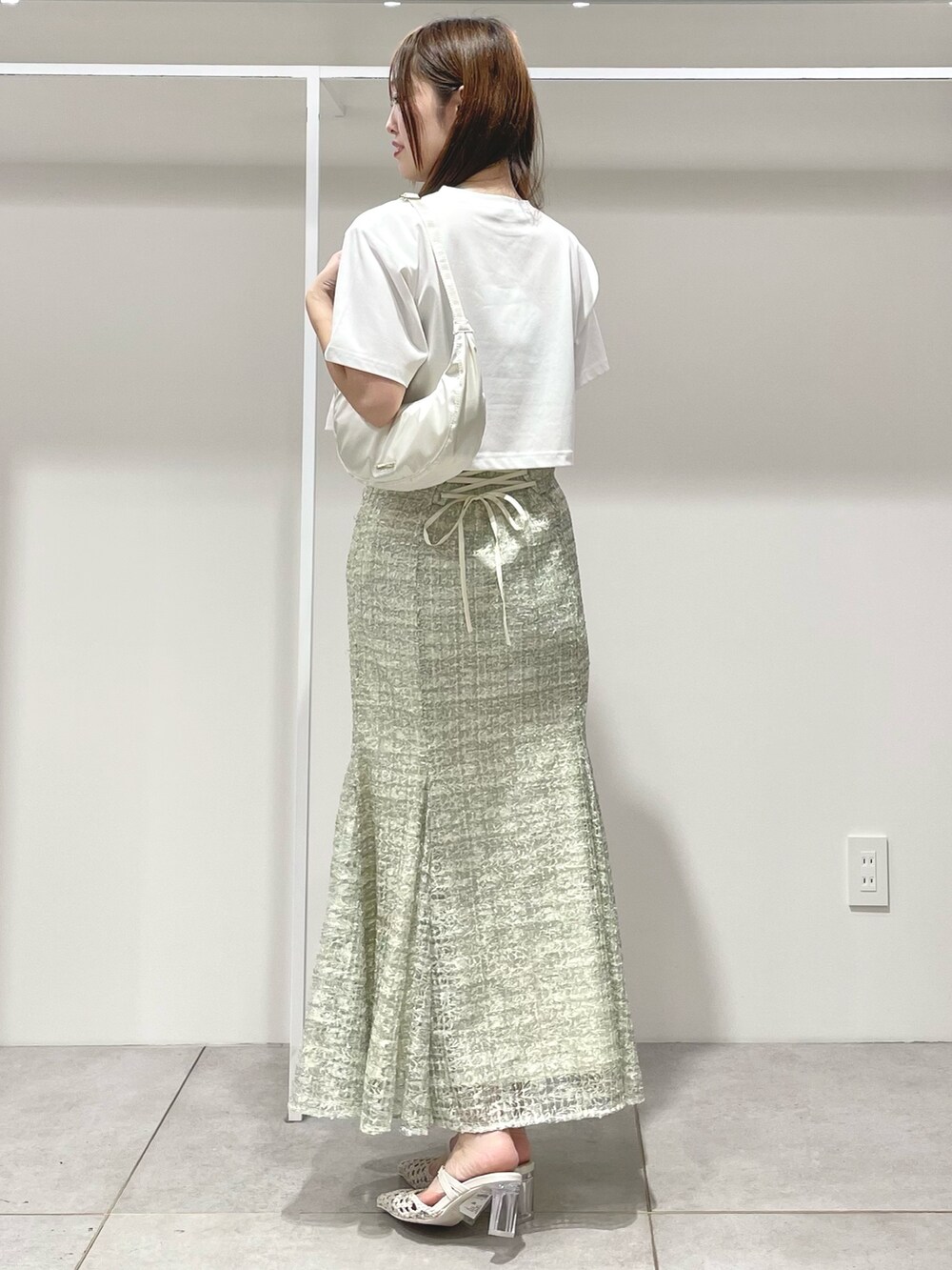 ホワイト系のTシャツ/カットソー、ホワイト系のショルダーバッグ、グリーン系のスカートを着用したレディースの春コーディネートの2枚目の写真