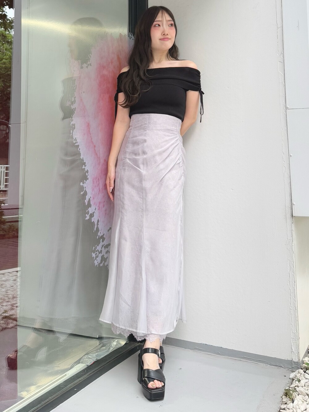 パープル系のスカート、ブラック系のニット/セーター、ブラック系のサンダルを着用したレディースの夏コーディネートの2枚目の写真