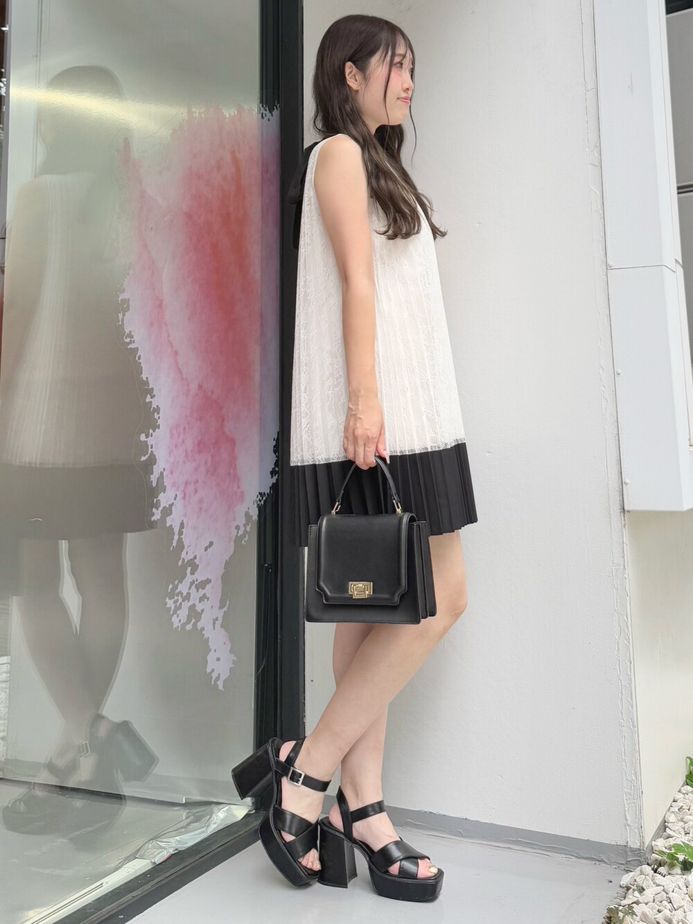 ホワイト系のワンピース、ブラック系のハンドバッグ、ブラック系のサンダルを着用したレディースの夏コーディネートの3枚目の写真