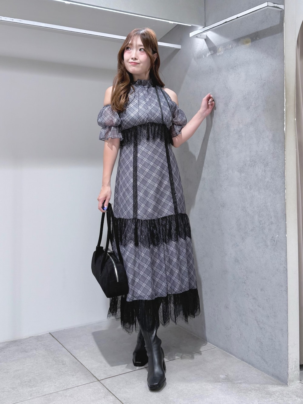 ブラック系のワンピース、ブラック系のハンドバッグ、ブラック系のブーツを着用したレディースの夏コーディネートの2枚目の写真