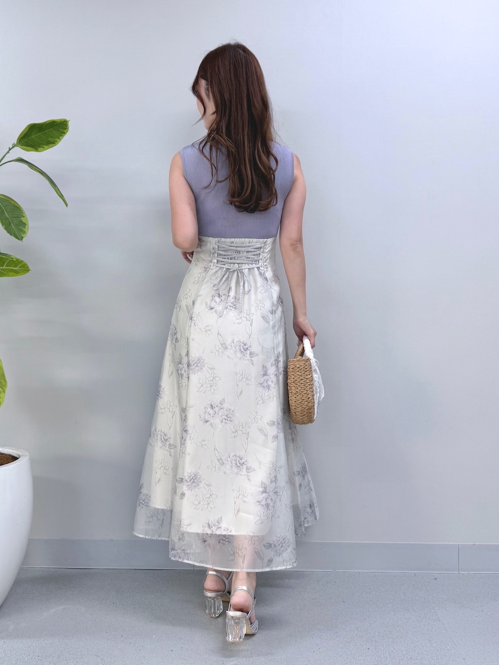 パープル系のワンピース、ベージュ系のハンドバッグ、シルバー系のサンダルを着用したレディースの夏コーディネートの3枚目の写真