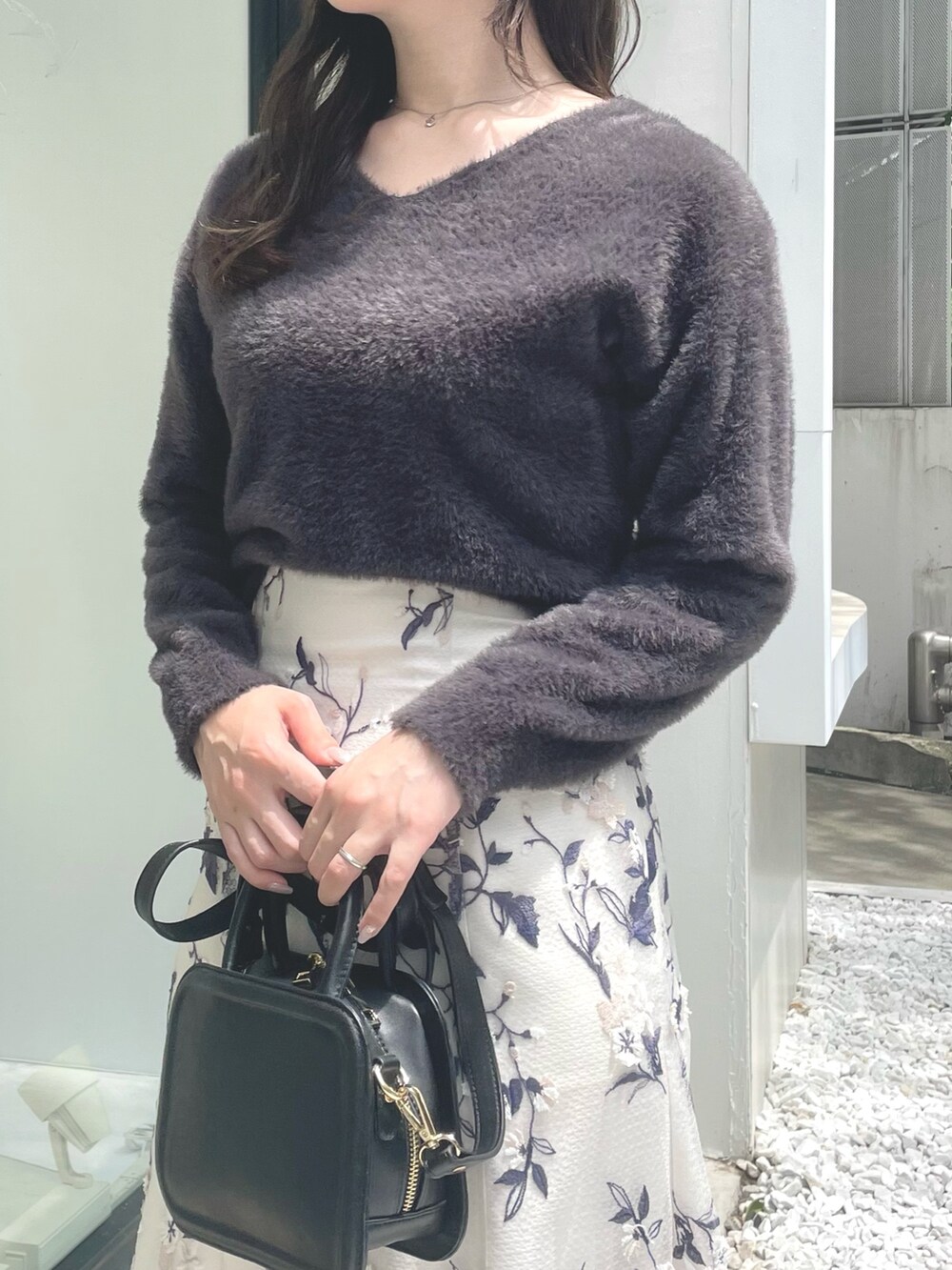 ブラック系のハンドバッグ、ブラウン系のブーツ、グレー系のスカートを着用したレディースの秋コーディネートの4枚目の写真