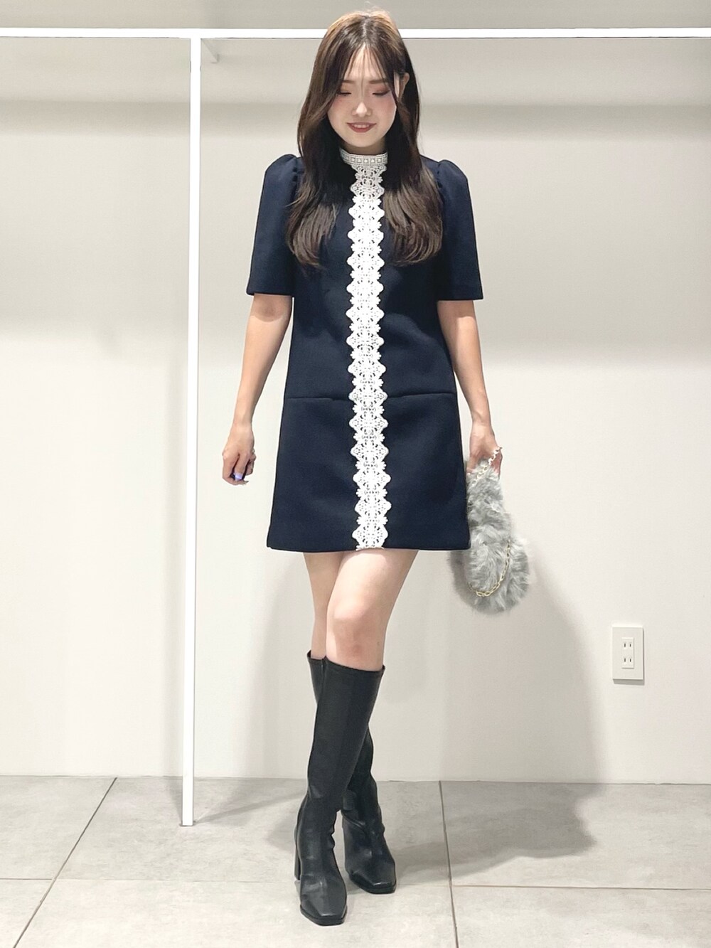 ブルー系のワンピース、ブラック系のブーツ、グレー系のハンドバッグを着用したレディースの秋コーディネートの2枚目の写真