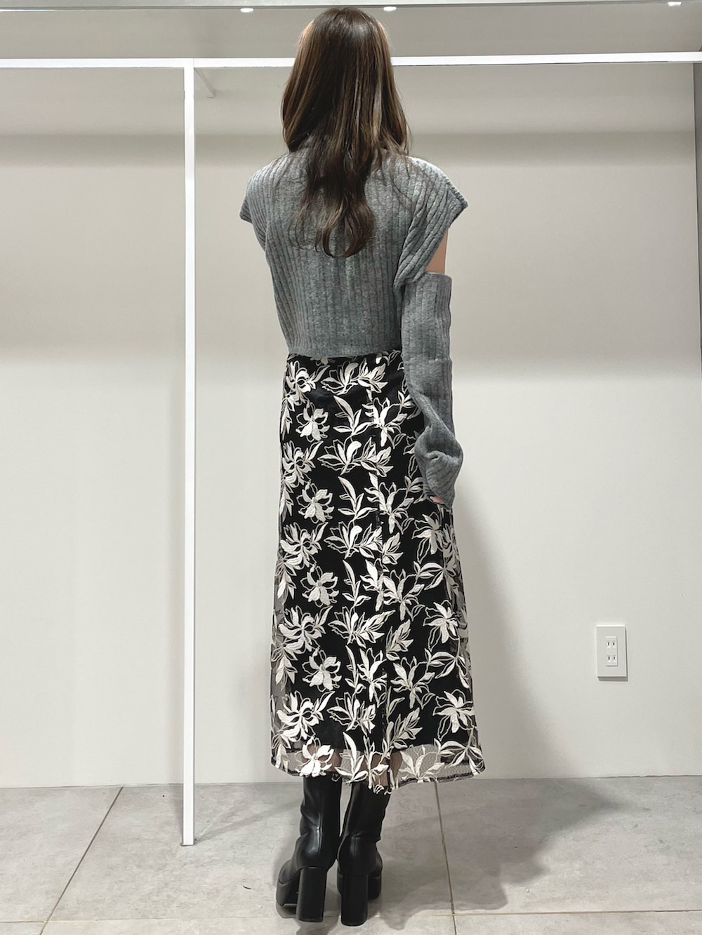 ブラック系のスカート、ブラック系のブーツ、グレー系のニット/セーターを着用したレディースの冬コーディネートの3枚目の写真