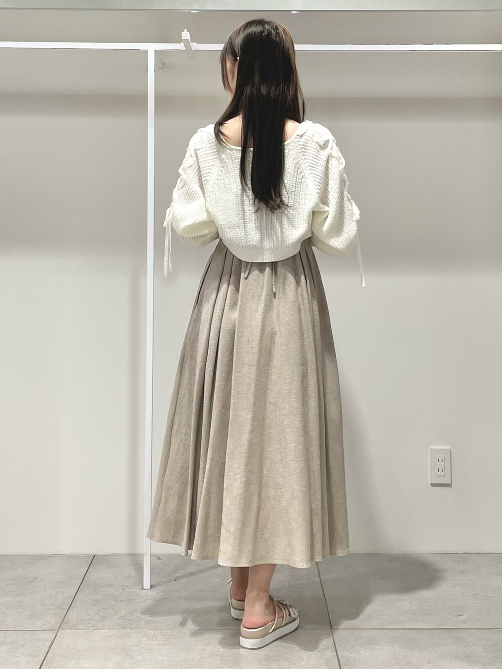 ベージュ系のワンピース、ホワイト系のカーディガン/ボレロ、ベージュ系のサンダルを着用したレディースの夏コーディネートの4枚目の写真