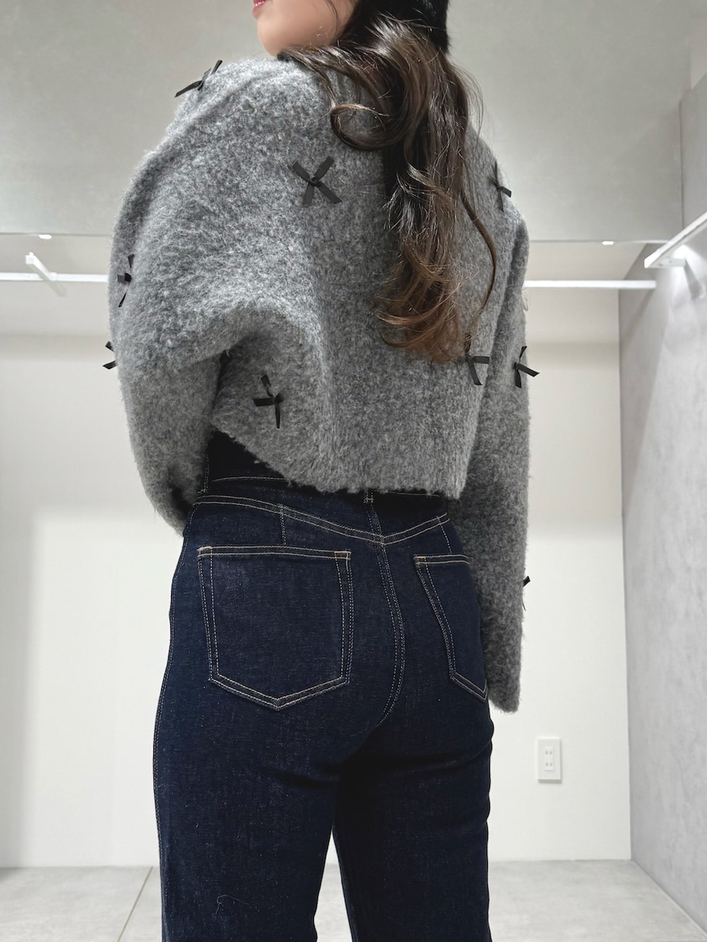 グレー系のカーディガン/ボレロ、ブルー系のデニムパンツ、ホワイト系のショルダーバッグを着用したレディースの冬コーディネートの6枚目の写真