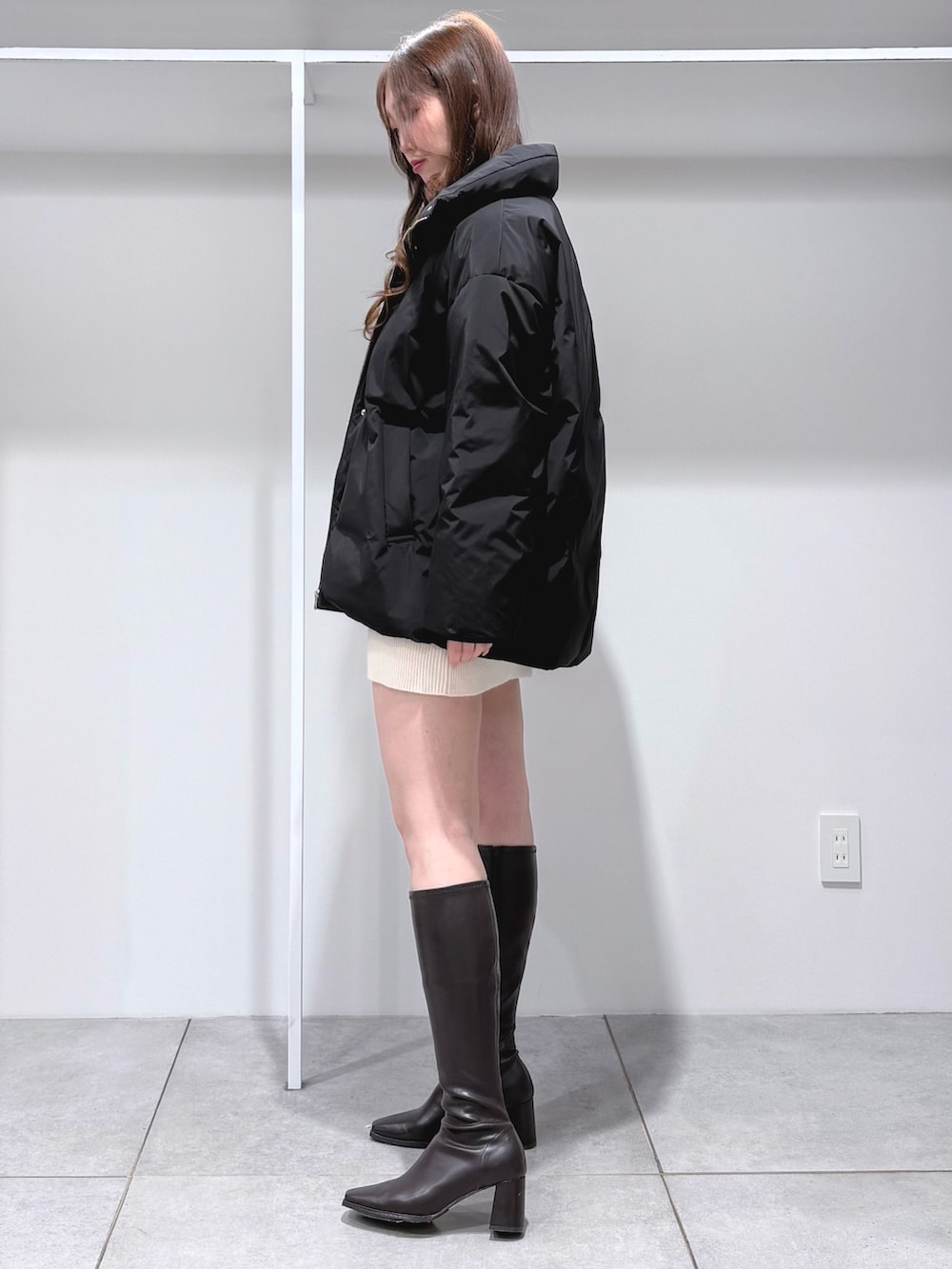 ホワイト系のワンピース、ブラウン系のブーツ、ブラック系のダウンジャケット/コートを着用したレディースの冬コーディネートの2枚目の写真