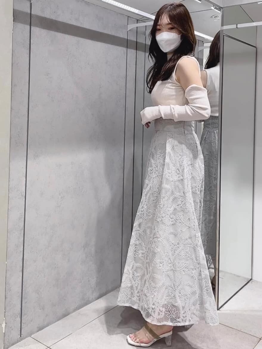 グリーン系のスカート、グリーン系のサンダル、ホワイト系のニット/セーターを着用したレディースの夏コーディネートの2枚目の写真